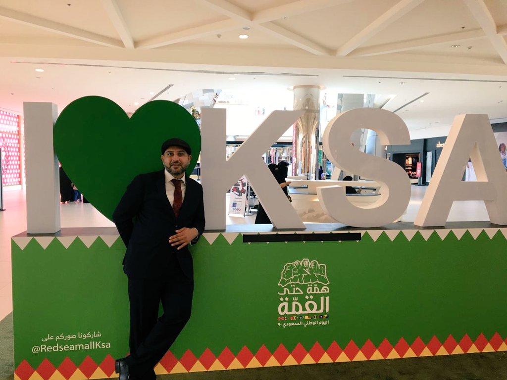 Mohsin Tutla leaning on a giant I love KSA sign decorated for Saudi National Day in a shopping mall