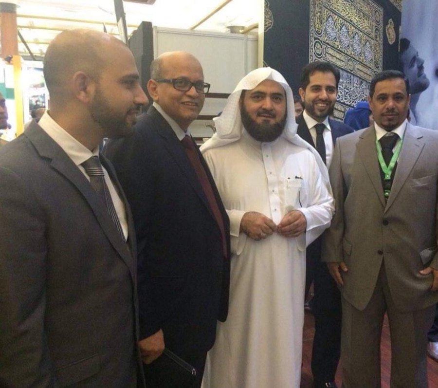 Mohsin Tutla with guests in front of a Kiswa display at an exhibition