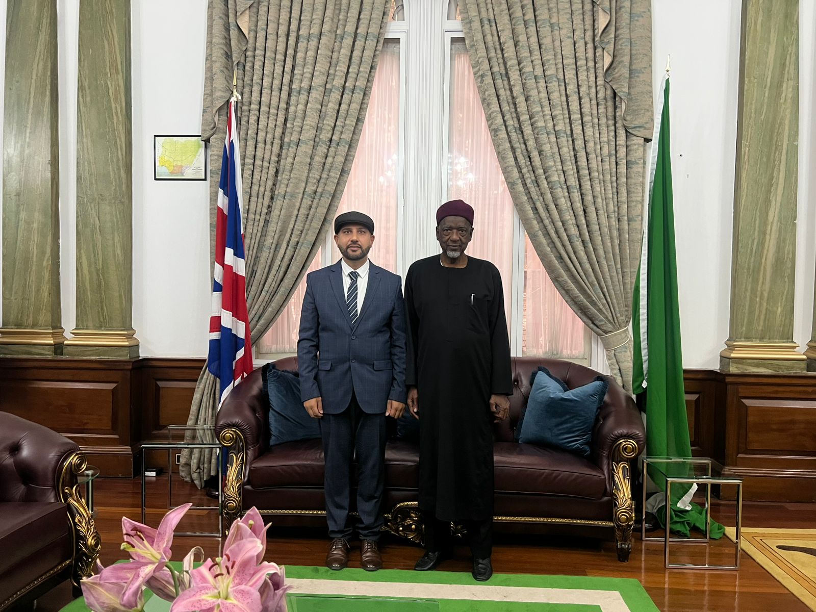 Mohsin Tutla standing beside a senior Nigerian dignitary in a formal reception room