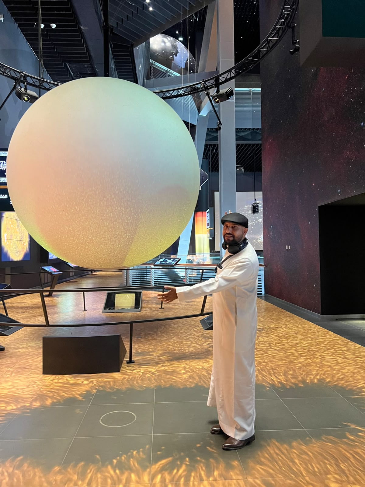 Mohsin Tutla standing beside a large planet model in a museum
