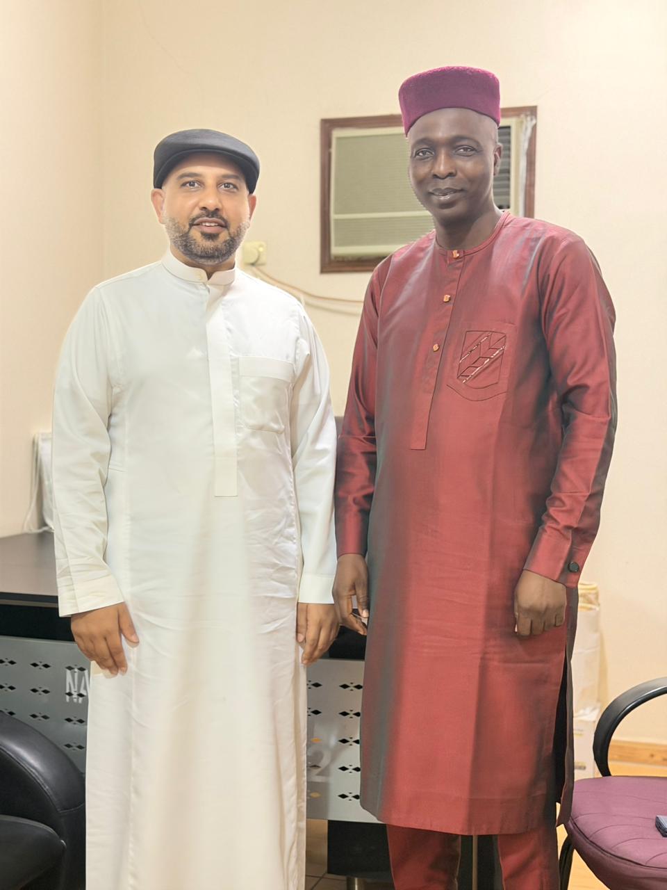 Mohsin Tutla in a white thobe standing with a man in red Nigerian attire